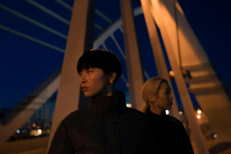 two people walking across a bridge at night, an album cover, inspired by Liam Wong, pexels contest winner, realism, model wears a puffer jacket, two women, still from the movie ex machina, ethnicity : japanese