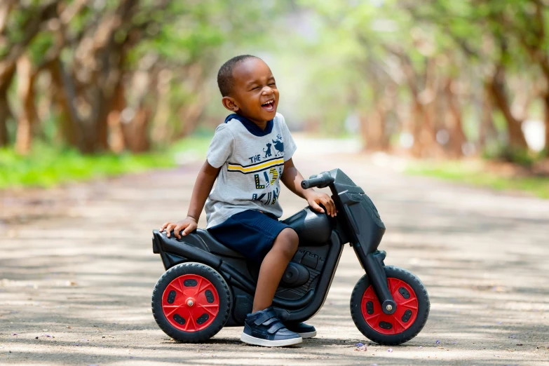 a little boy that is sitting on a scooter, by Joze Ciuha, pexels contest winner, photorealism, excited, emmanuel shiru, 4yr old, black