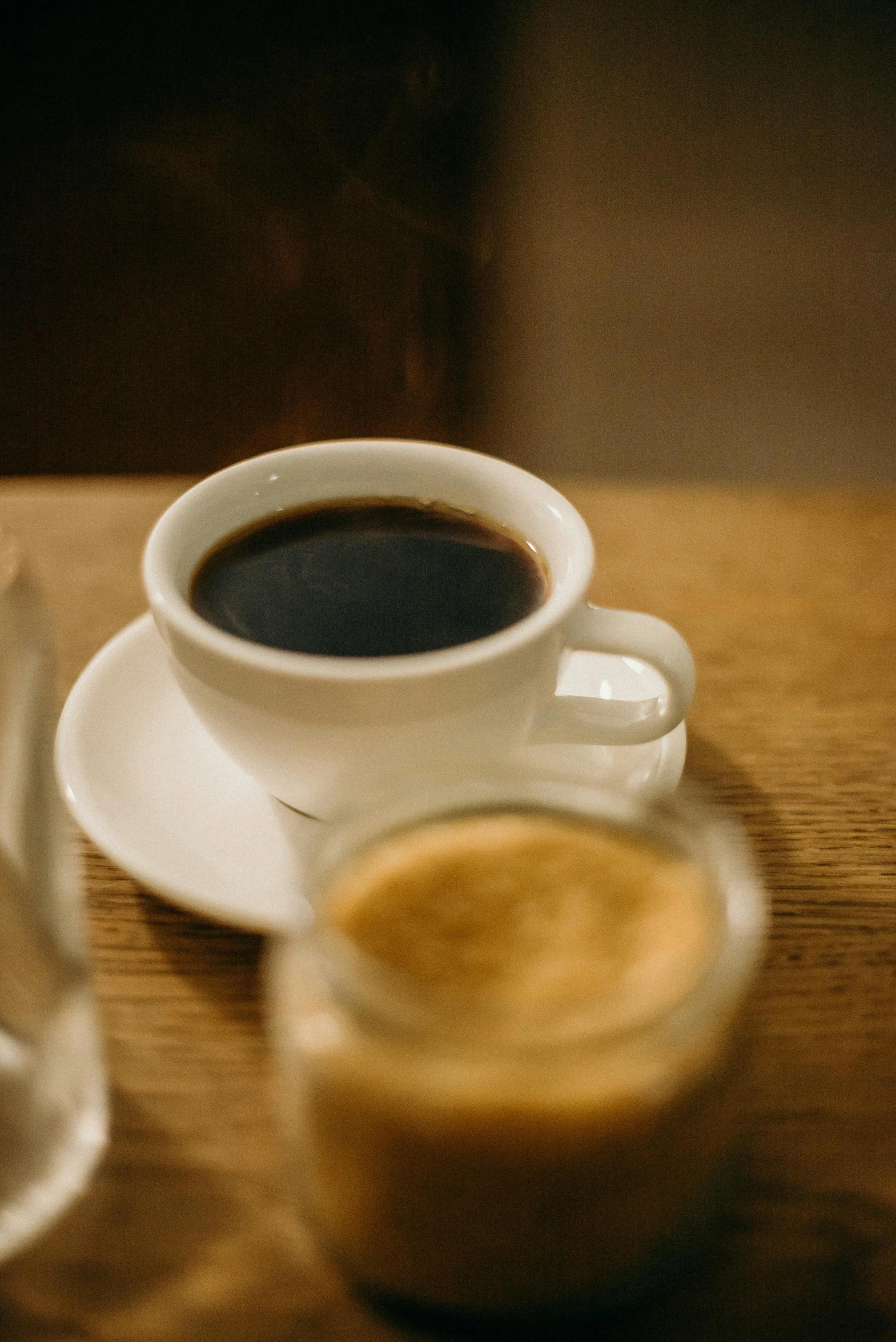 a cup of coffee sitting on top of a wooden table, two cups of coffee, zoomed in, 2019 trending photo, ad image