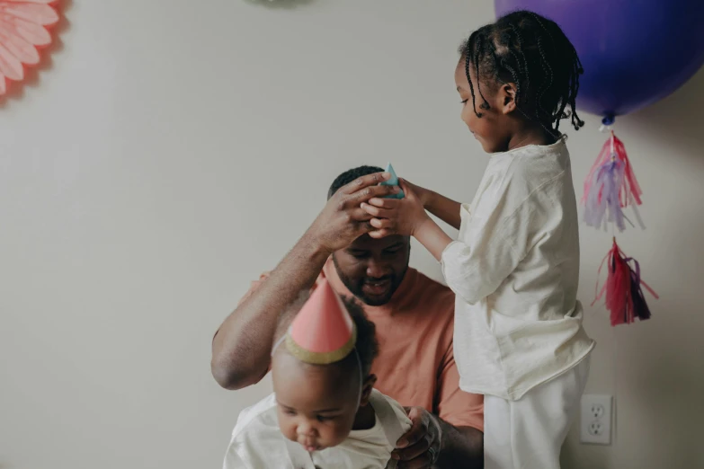 a man is combing a little girl's hair, pexels contest winner, afrofuturism, party hats, portrait of family of three, daddy/fatherly, thumbnail