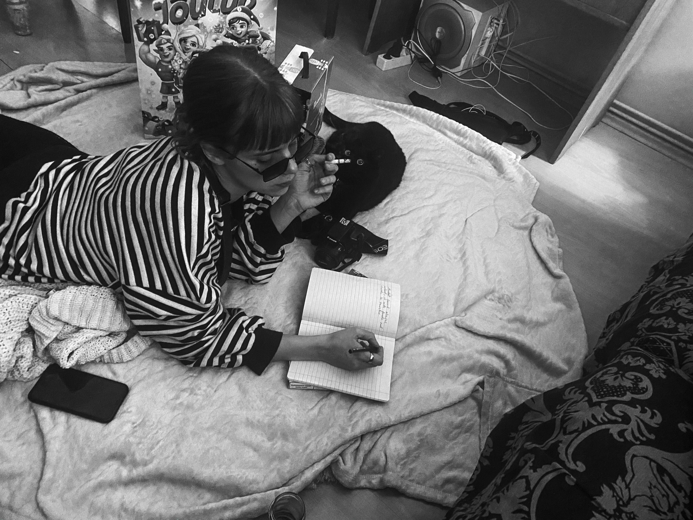 a woman laying on a bed reading a book, a black and white photo, instagram, op art, charli xcx, writing in journal, with cats on her side, some glints and specs