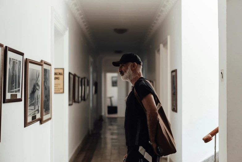 a man that is standing in a hallway, a photo, by Emma Andijewska, pexels contest winner, visual art, old gigachad with grey beard, college, tom of finland, tourist photo