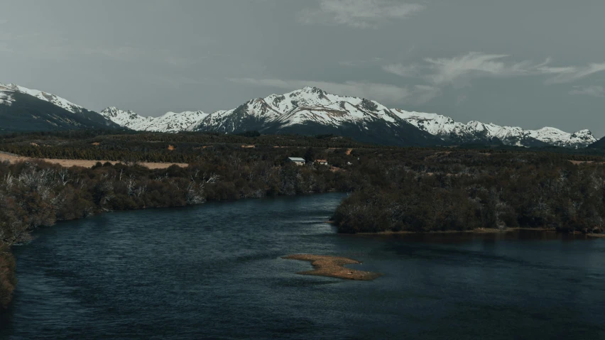 a body of water with mountains in the background, by Pablo Rey, pexels contest winner, hurufiyya, snowy mountains, how a river, movie still 8 k, grey