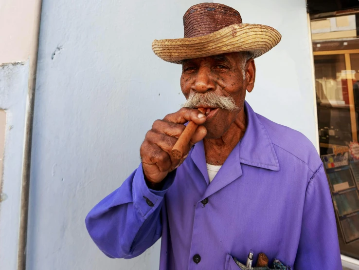 a man in a straw hat smokes a cigar, pexels contest winner, cuban setting, wearing a purple cap, oldman with mustach, reuters