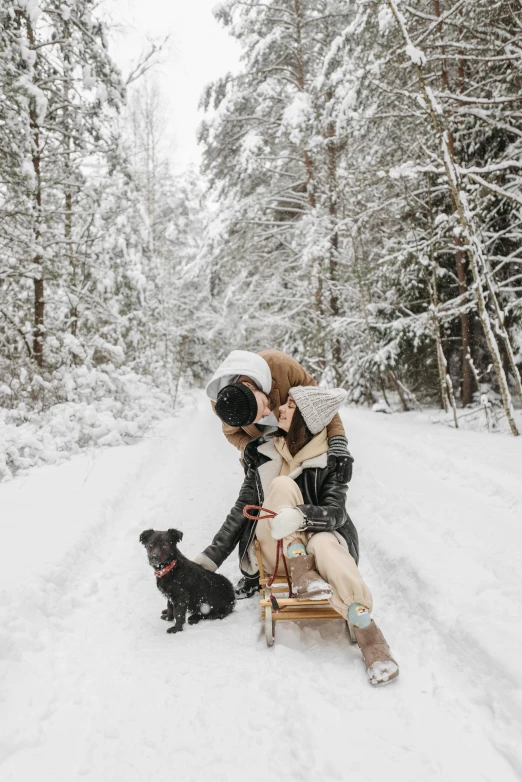 a man and woman sitting on a sled in the snow with a dog, by Emma Andijewska, pexels contest winner, romanticism, gif, holding each other, vine, white