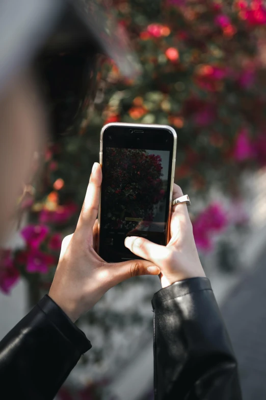 a woman taking a picture with her cell phone, trending on unsplash, happening, with soft bushes, wearing a dark shirt and jeans, flowery, like a catalog photograph