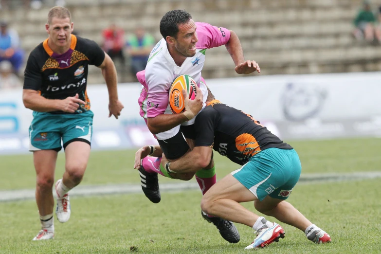 a group of men playing a game of rugby, pink white and green, diego fernandez, profile pic, ground level shot