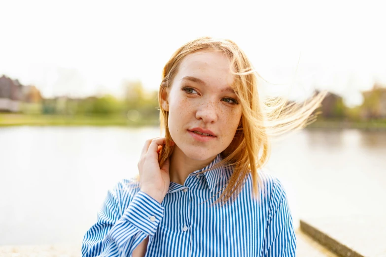 a woman standing next to a body of water, sydney sweeney, wearing stripe shirt, very light freckles, avatar image