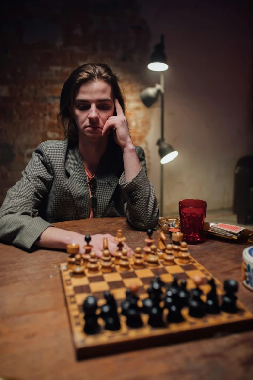 a woman sitting at a table with a chess board, a portrait, by Adam Marczyński, unsplash, movie still of a tired, promo image, annoyed, playing