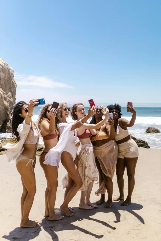 a group of women standing on top of a sandy beach, taking selfies, malibu canyon, at a fashion shoot, tan skin