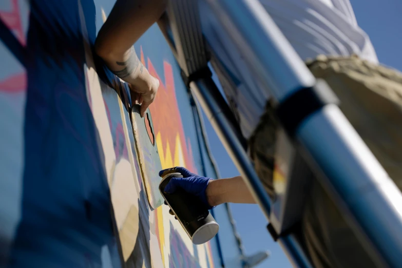 a man is painting a mural on the side of a bus, by karlkka, pexels contest winner, prussian blue and azo yellow, low - angle shot, avatar image, james gilleard and james jean