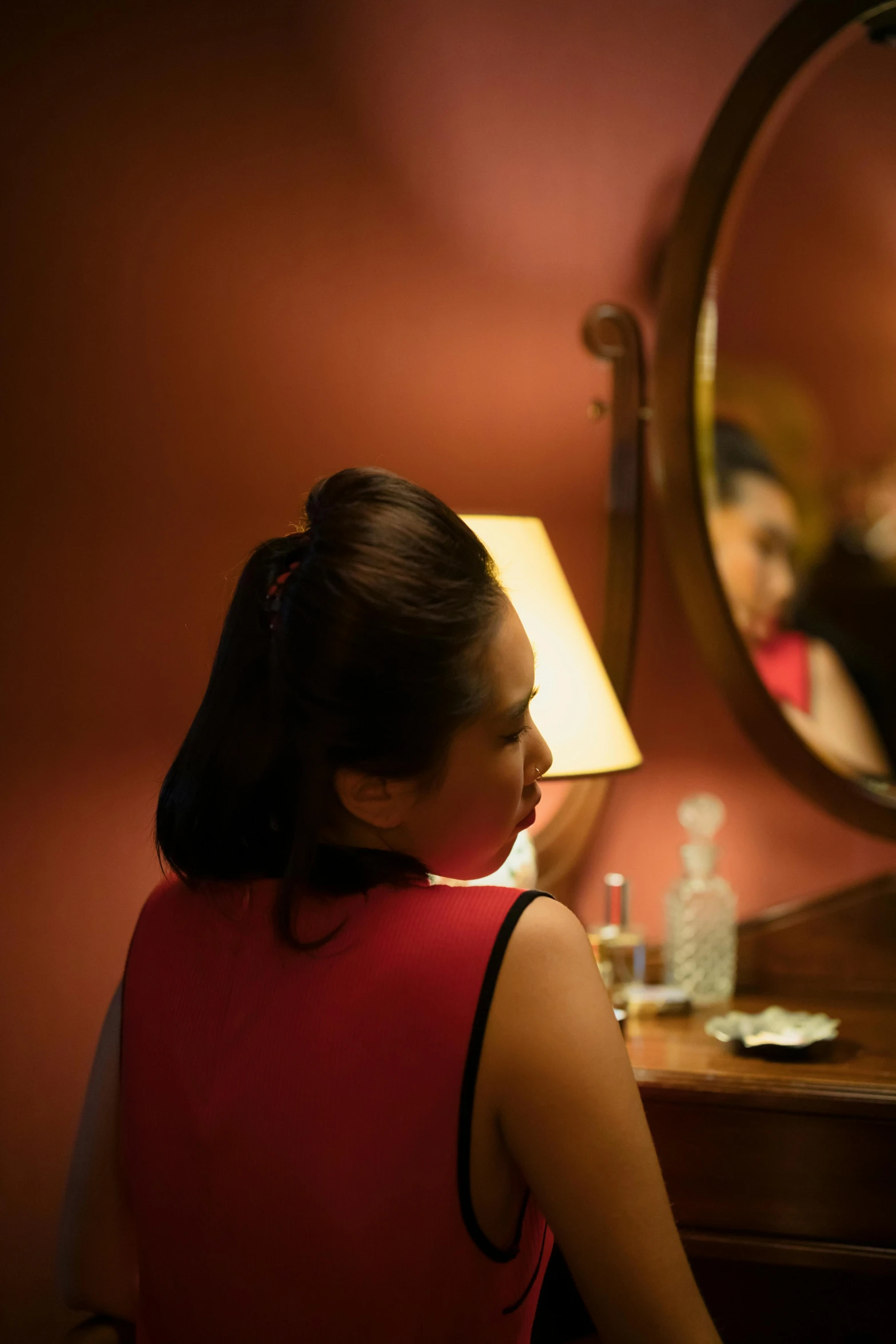 a woman looking at her reflection in a mirror, a portrait, inspired by Nan Goldin, happening, cheongsam, red room, soft lighting |, woman's profile