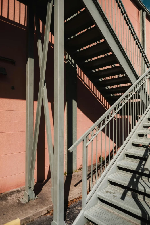 a set of stairs going up the side of a building, by Doug Ohlson, payne's grey and venetian red, afternoon light, metalwork, pink shadows