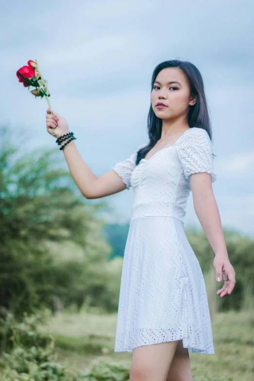 a woman in a white dress holding a red rose, inspired by Juan Luna, unsplash, young asian girl, wearing a white folkdrakt dress, threatening pose, 5 0 0 px models