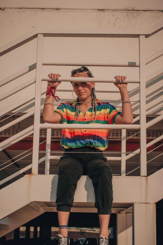 a man sitting on top of a stair rail, rainbow accents, islandpunk, non-binary, wearing a bandana and chain