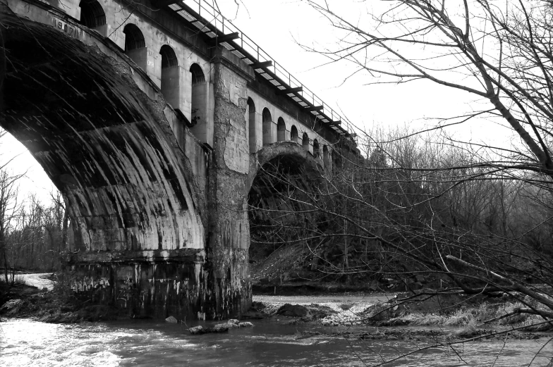 a black and white photo of a bridge over a river, by David Palumbo, renaissance, abandoned railroads, seen from the side, tall arches, post grunge