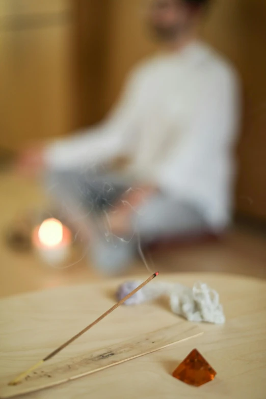 a man sitting on the floor in front of a laptop, by Elizabeth Durack, unsplash, process art, incense, blurred detail, spa, holding a wooden staff