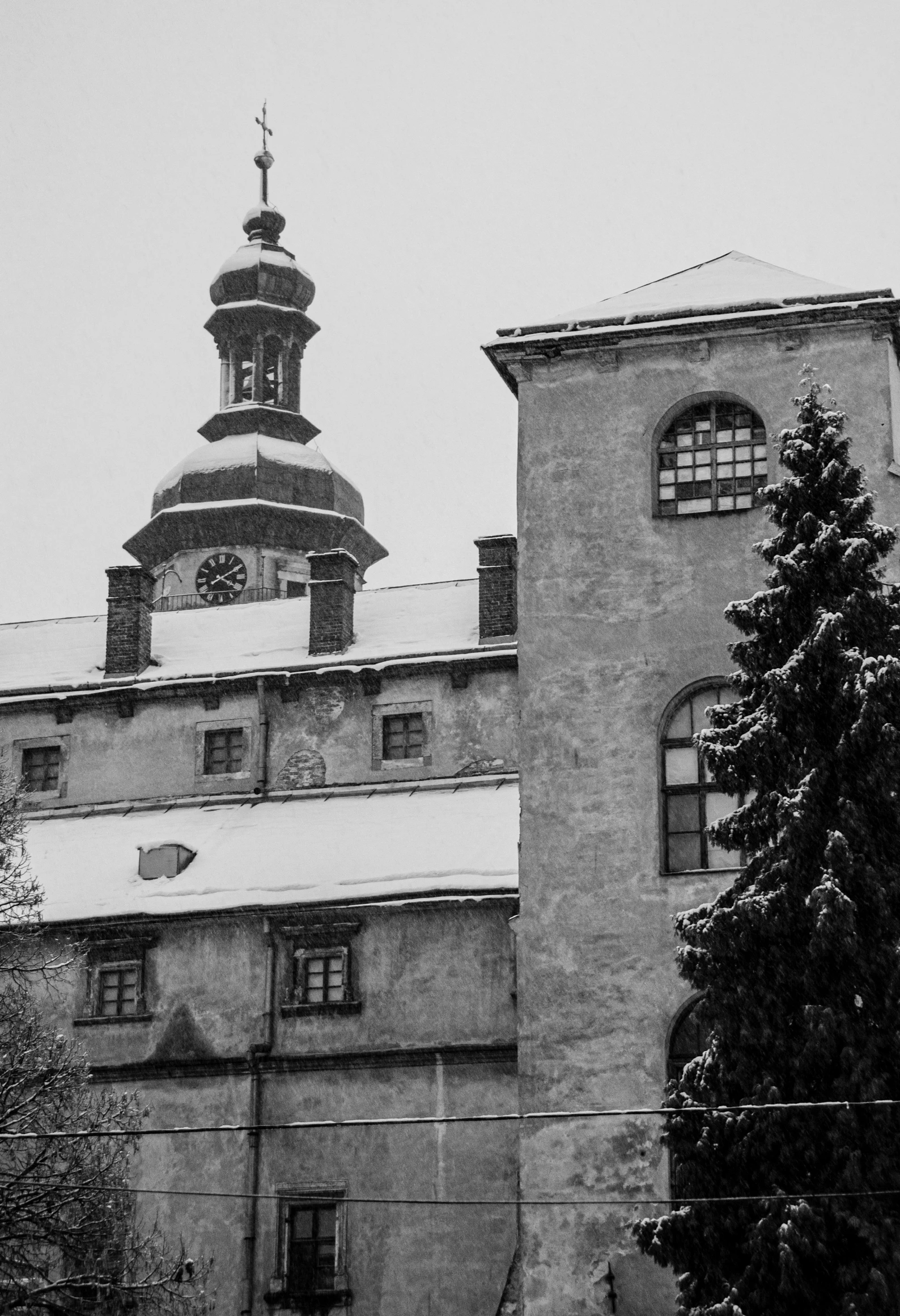 a black and white photo of a building with a clock tower, inspired by Wojciech Weiss, baroque, snowfall, castle on the mountain, post - soviet courtyard, sedlec ossuary