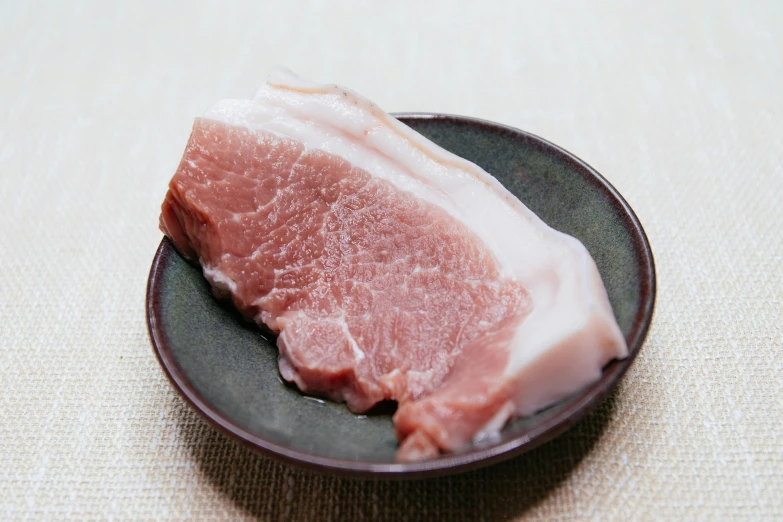 a piece of meat on a plate on a table, sōsaku hanga, wide neck, organic flesh, pale head, full product shot