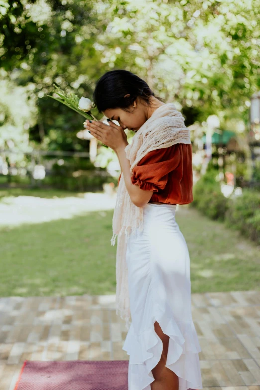 a woman standing on top of a yoga mat, inspired by Ruth Jên, unsplash, renaissance, white scarf, in garden, head bowed slightly, myanmar