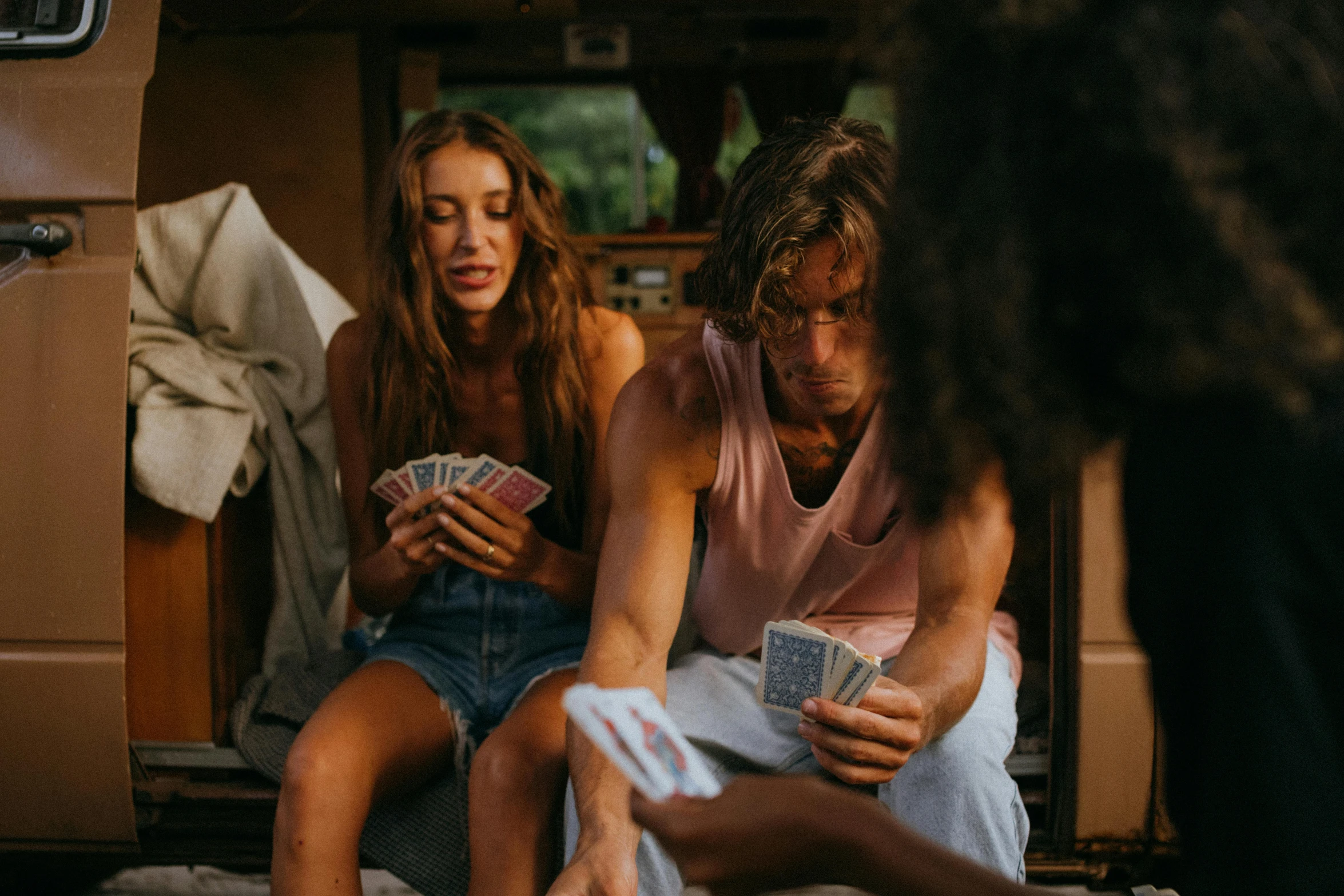 a man and a woman playing cards in the back of a van, pexels contest winner, wearing a tank top and shorts, jamie campbell bower, holding court, woman holding another woman