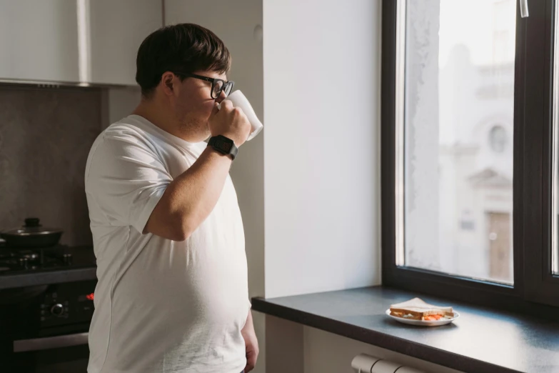 a man standing in front of a window drinking from a cup, extremely fat, people inside eating meals, profile image, man with glasses