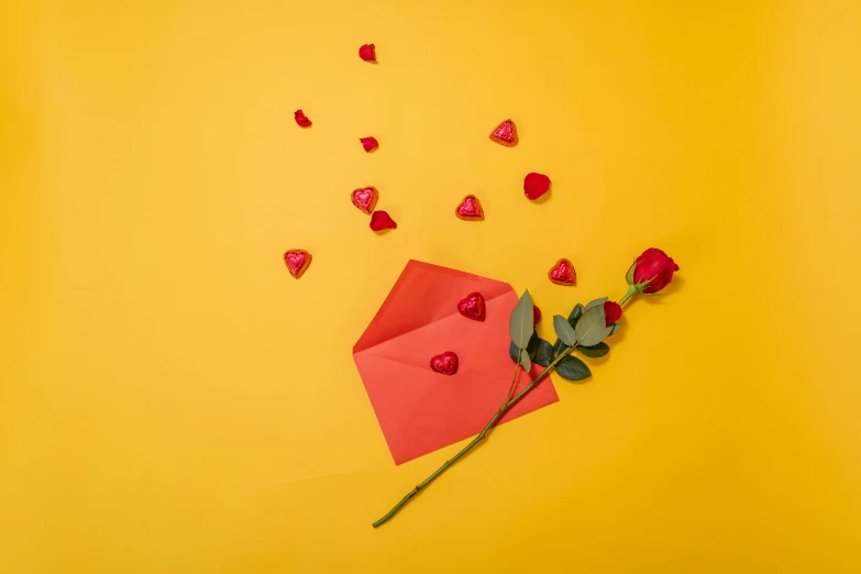 a red envelope and a red rose on a yellow background, by Julia Pishtar, pexels contest winner, romanticism, candy decorations, balloon, “diamonds, long petals