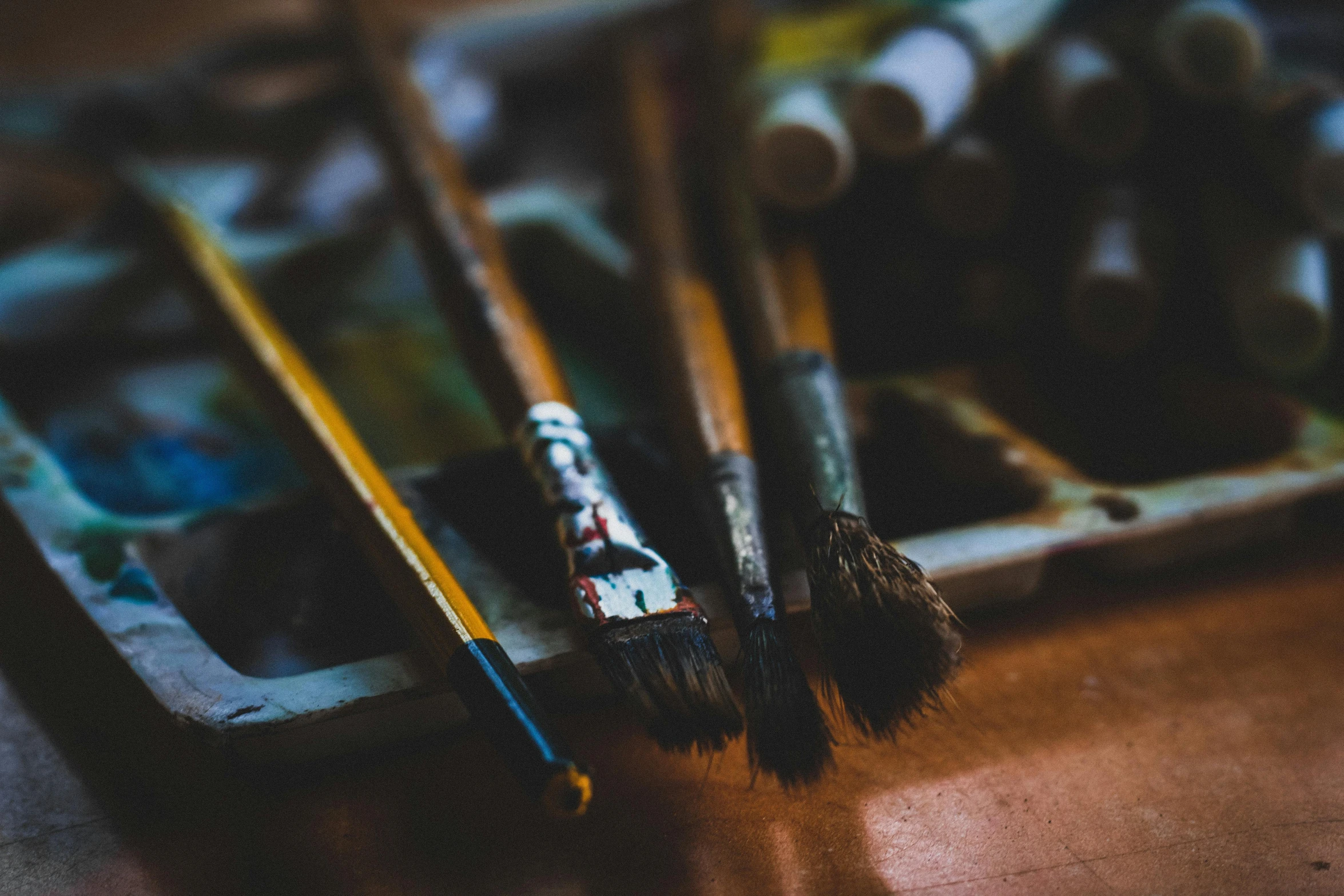 a bunch of paint brushes sitting on top of a wooden table, by Andrée Ruellan, pexels contest winner, visual art, 🎨🖌, grungy, on canvas, brown