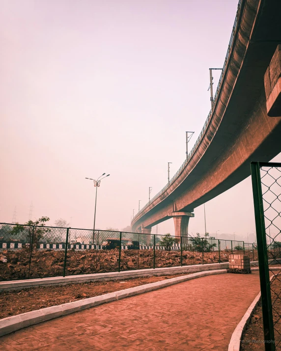 a man riding a skateboard down a sidewalk next to a bridge, an album cover, unsplash contest winner, beautiful futuristic new delhi, dust clouds | homoerotic, terracotta, monorail