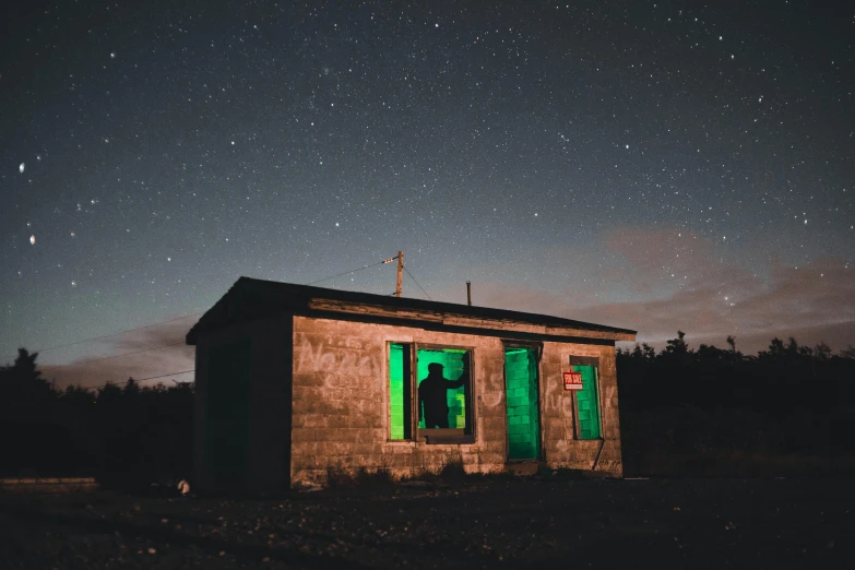 a small building sitting in the middle of a field, an album cover, pexels contest winner, magical realism, green neon, watching the stars at night, profile image, standing outside a house