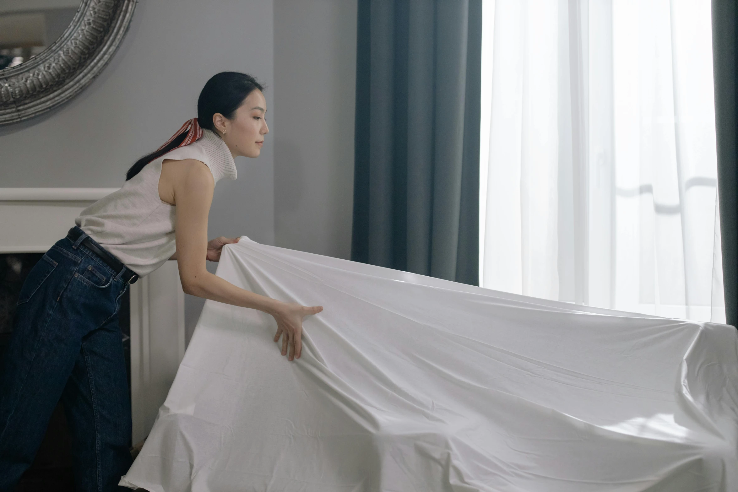 a woman putting a sheet on top of a bed, inspired by Fei Danxu, hotel room, cloth simulation, grey