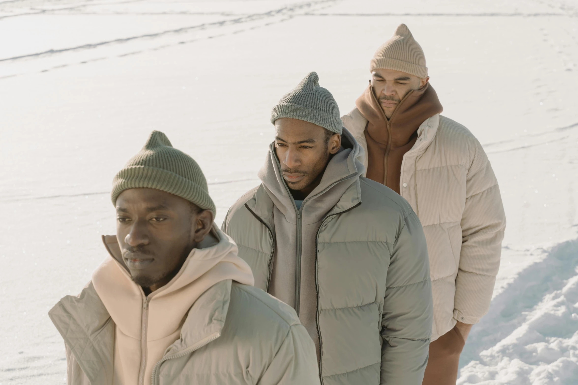 a group of men standing next to each other in the snow, inspired by Barthélemy Menn, trending on pexels, model wears a puffer jacket, simple muted colors, ignant, thumbnail