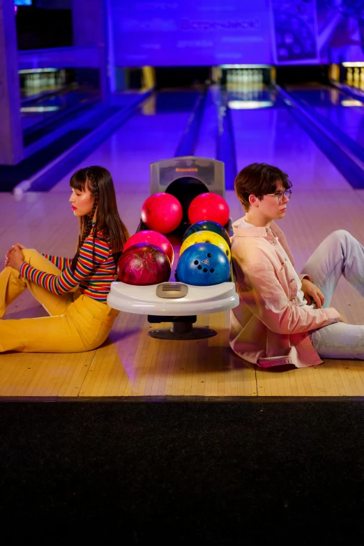 a group of people sitting next to each other on a bowling court, an album cover, trending on pexels, hailee steinfeld, purple and pink and blue neons, medium shot of two characters, boy and girl