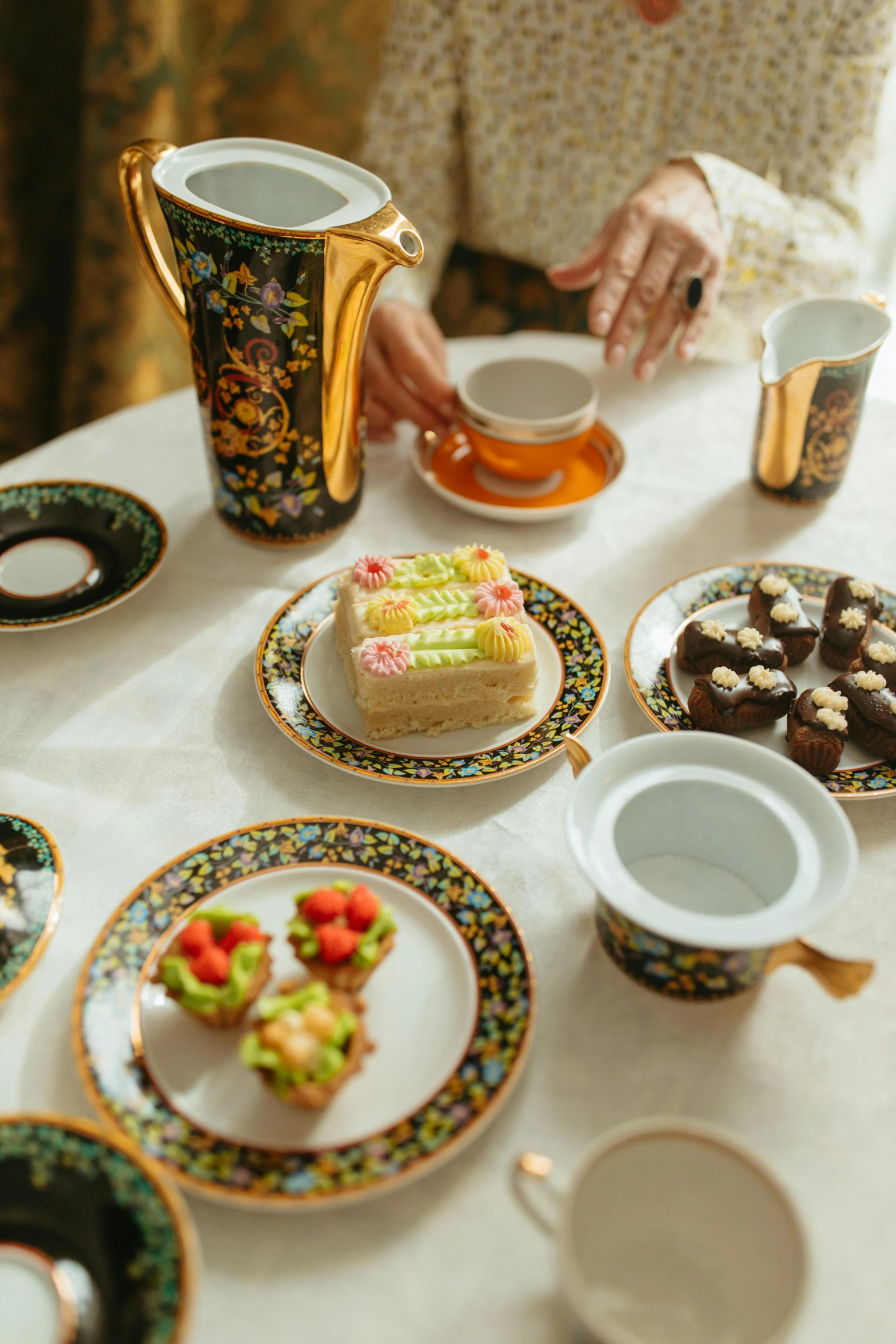 a woman sitting at a table with plates of food, arabesque, engalnd porcelain tea set, cakes, azamat khairov, and