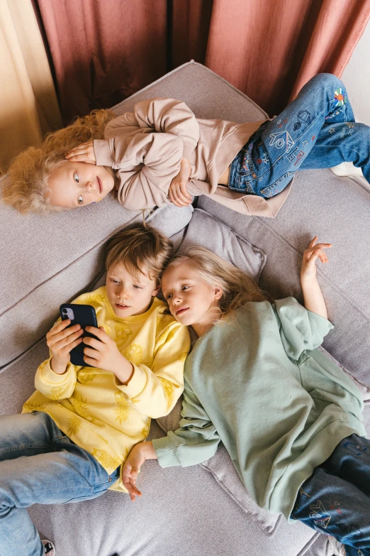 a group of people laying on top of a couch, trending on pexels, kids playing, phone photo, blond, threes