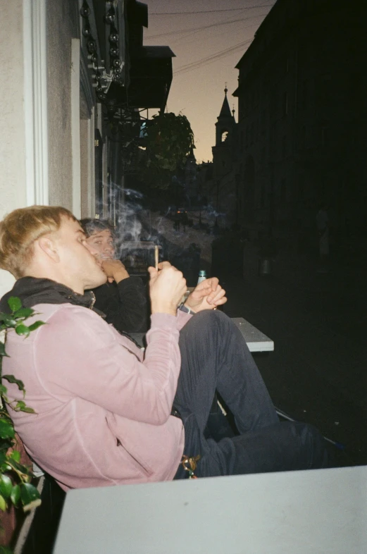 a woman sitting on a window sill smoking a cigarette, a polaroid photo, unsplash, two young men, evening time, a blond, on sidewalk