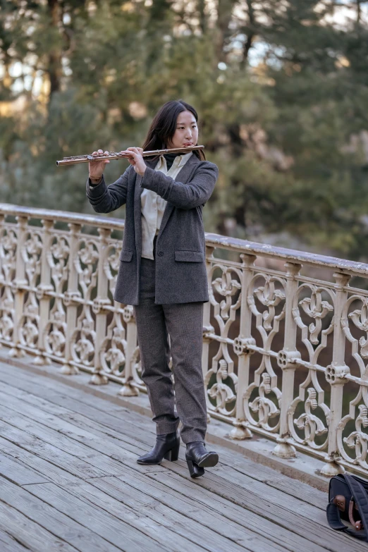 a woman playing a flute on a bridge, inspired by Fei Danxu, unsplash, baroque, humans of new york, asian man, in the styles of thomas eakins, medium-shot