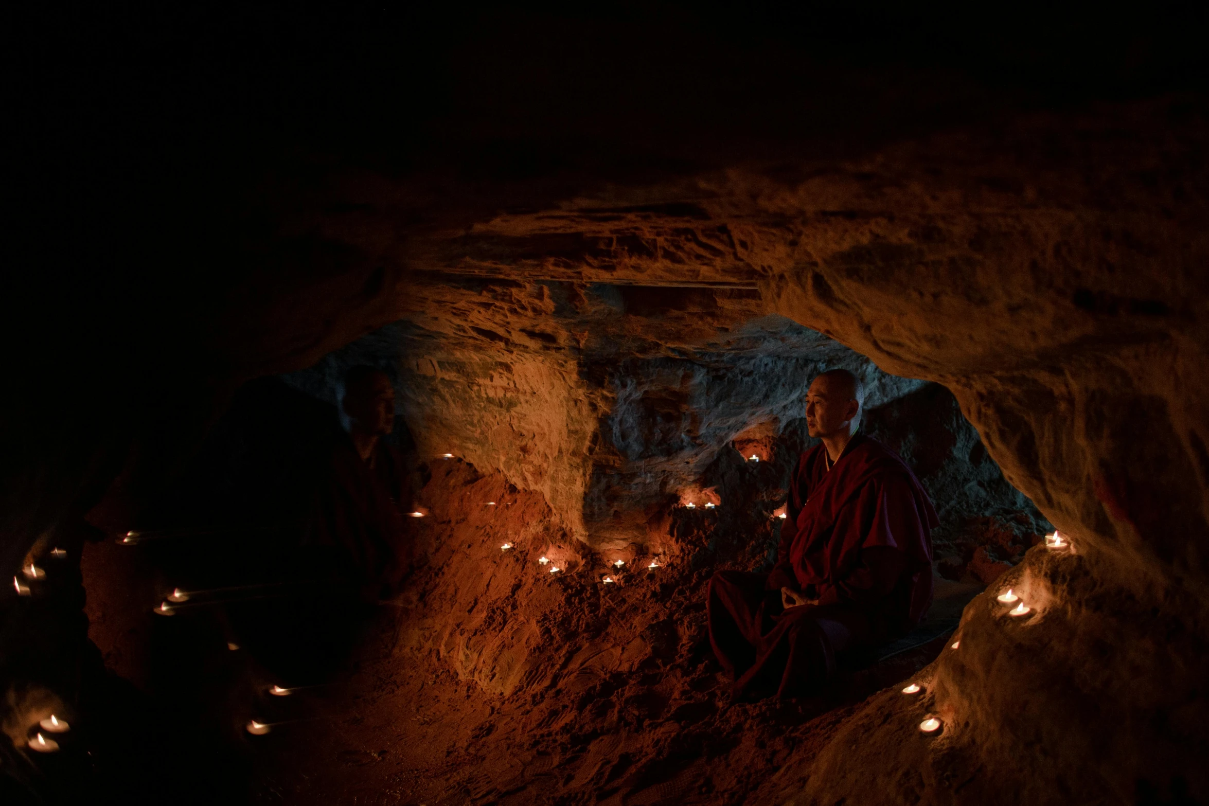 a group of monks sitting in a cave with candles, lpoty, photograph, underground city, taken with sony alpha 9