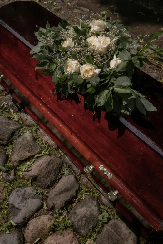 a casket with a bunch of flowers on top of it, face down, historical setting, shot with sony alpha, high-angle