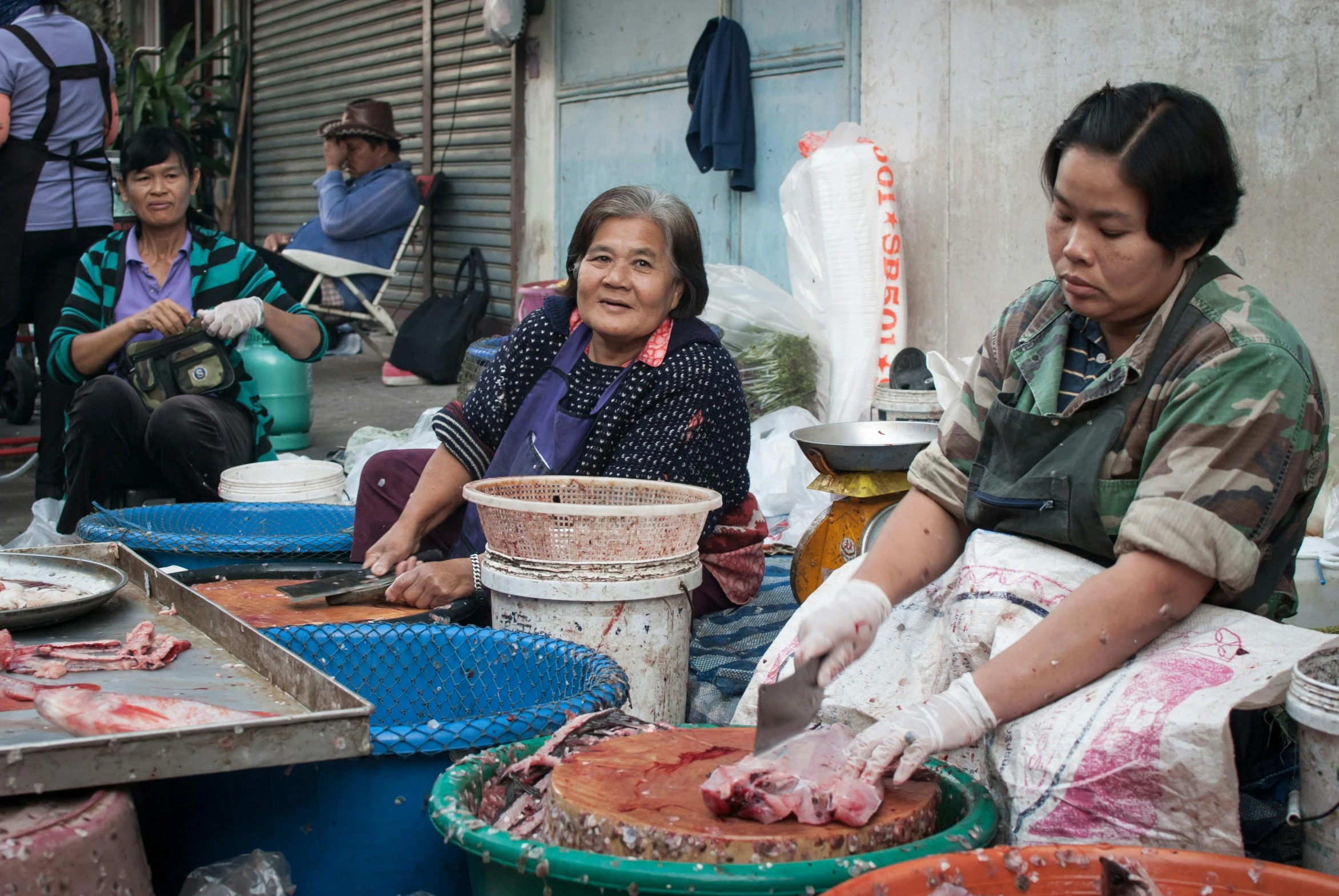 a couple of women sitting next to each other near buckets of food, gutai group, filleting technique, thumbnail, bangkok townsquare, rich decaying bleeding colors