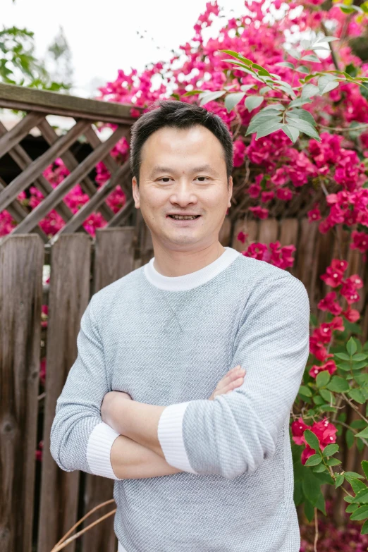 a man standing in front of a wooden fence, inspired by Chen Chun, flowers in background, professional profile picture, (38 years old), bay area