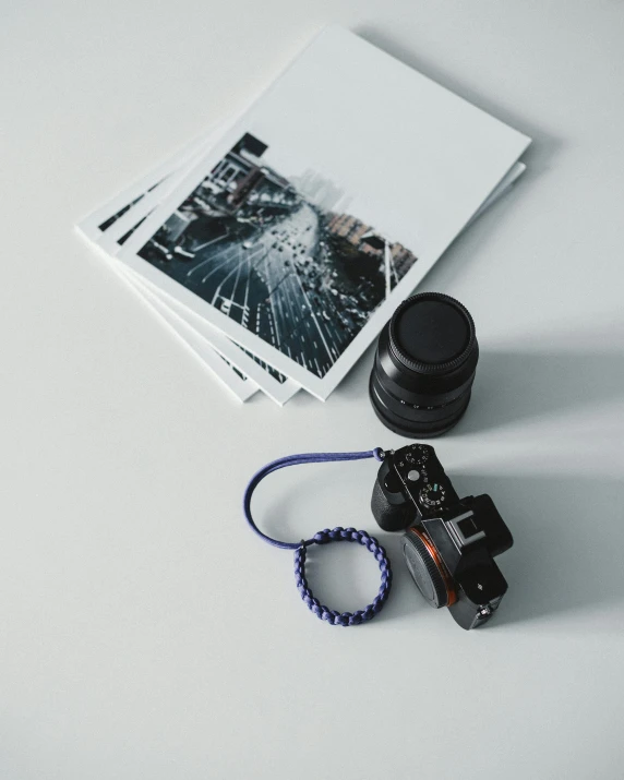 a camera sitting on top of a table next to a book, black and blue and purple scheme, product image, miscellaneous objects, on white paper