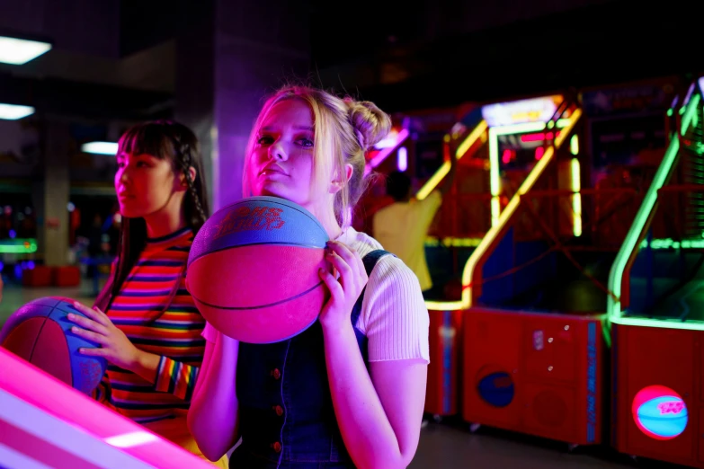 a woman holding a basketball while standing next to another woman, a busy arcade, pink and blue lighting, charli bowater and artgeem, princess in foreground