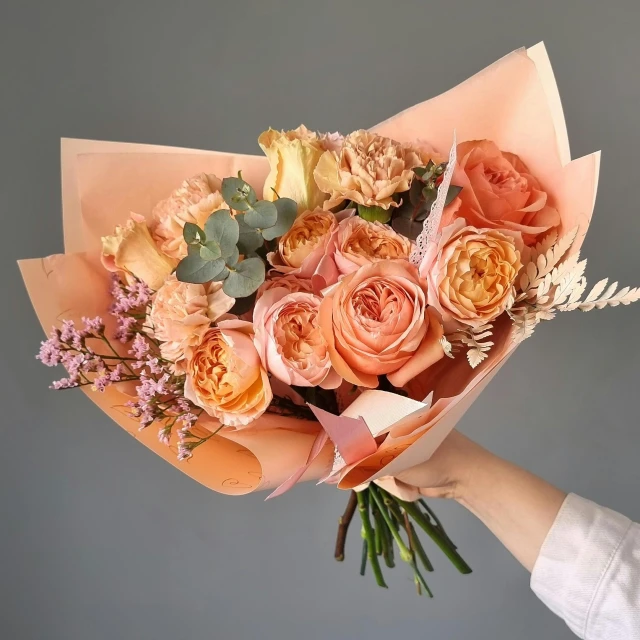 a close up of a person holding a bouquet of flowers, in shades of peach, on a gray background, fan favorite, cornucopia