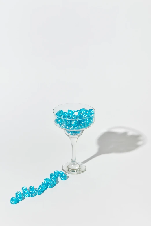 a glass filled with blue candy sitting on top of a table, beads, set against a white background, jen atkin, made of drink