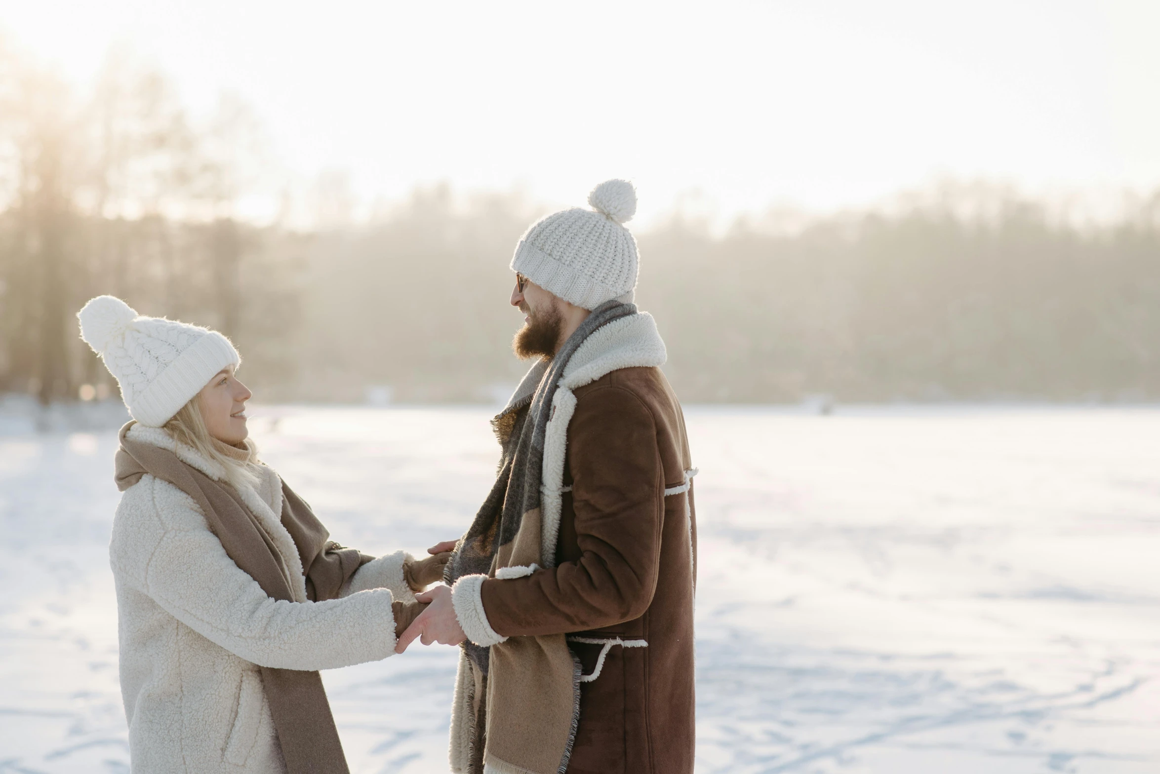 a man and woman holding hands in the snow, by Eero Järnefelt, pexels contest winner, smiling at each other, brown, white, promotional image