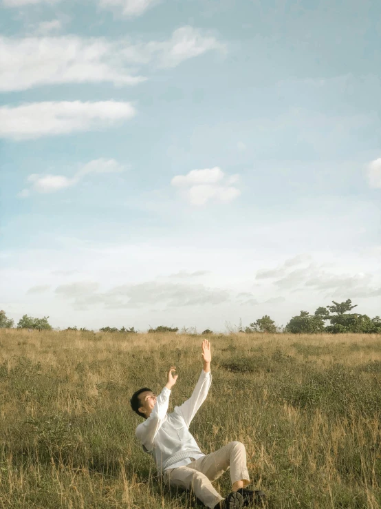 a man sitting in a field throwing a frisbee, an album cover, by Basuki Abdullah, unsplash, magical realism, uniform off - white sky, ignant, yoga, cai xukun