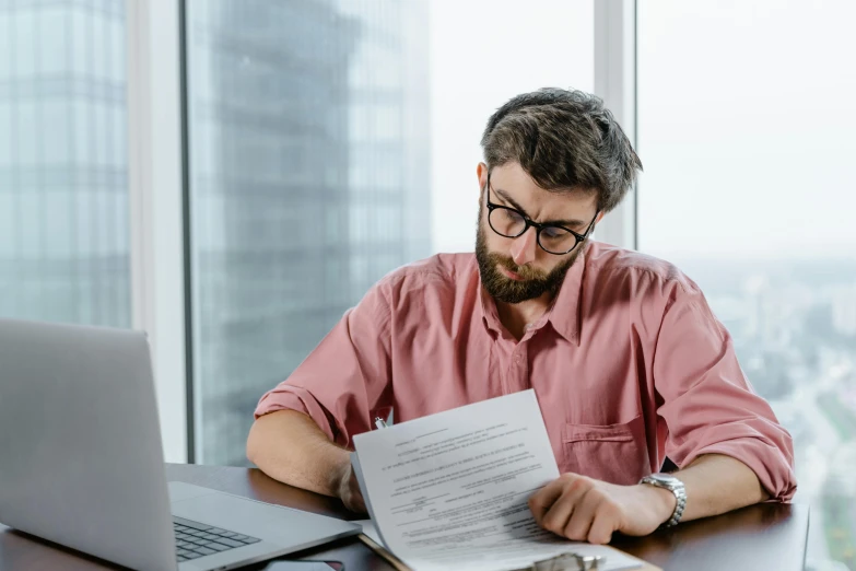 a man sitting at a table with a laptop and papers, a cartoon, pexels contest winner, trending on attestation, lachlan bailey, high quality photo, casually dressed