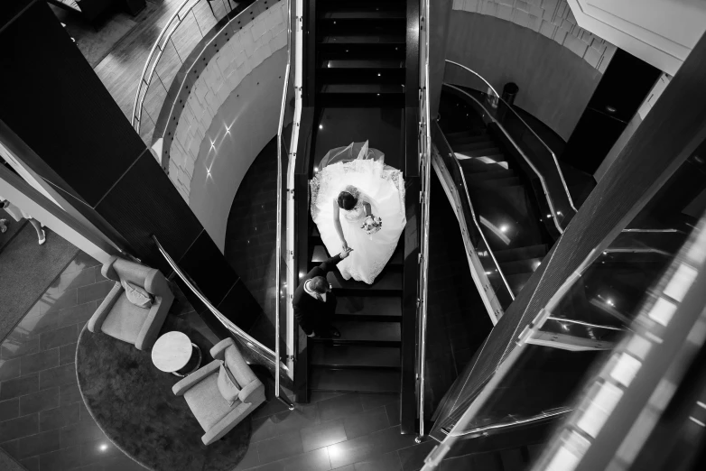 a black and white photo of a bride on an escalator, by Arthur Sarkissian, bird\'s eye view, luxurious environment, trending photo, bogdan rezunenko