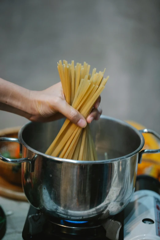 a person cooking spaghetti in a pot on a stove, pexels, with a straw, sleek hands, al fresco, gelatine silver process